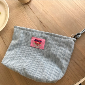 Blue striped denim toiletry bag with pink Sound of Silence patch and sturdy handle