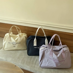 Detailed row of canvas Boston bags in white, black and purple with printed lettering