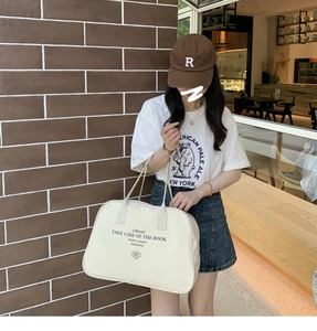 Detail of a large canvas Boston bag with minimalist text shown in a casual urban outfit