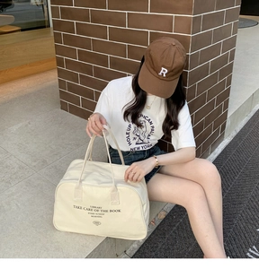 Overhead view of large off-white canvas Boston bag with library text print in retro style