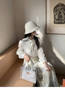 Detail of a floral lavender handbag paired with an elegant lace shirt and straw hat