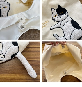 Detail view of canvas bag featuring cat embroidery, fluffy tail, and snap button closure