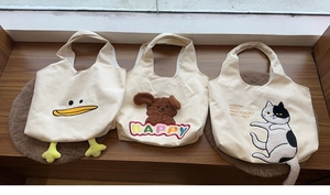 Detailed view of canvas tote bags featuring duck, puppy and cat 3D plush designs