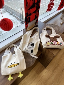 Detailed view of canvas tote bags featuring 3D animal embroidery and cute plush details