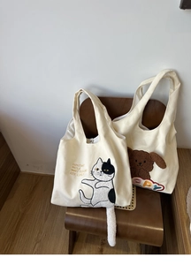 Detail of cute canvas tote bags with 3D cat tail and dog embroidery on wooden chair