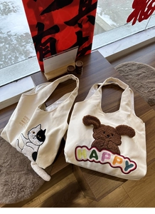 Detail of canvas tote bags with plush 3D cat tail and colorful HAPPY embroidery