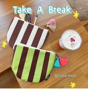 Close-up of striped canvas cosmetic bags with colorful tassels on a wooden surface