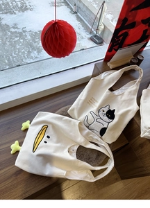 Detail of creative canvas tote bags featuring cute cat print and 3D plush duck feet design