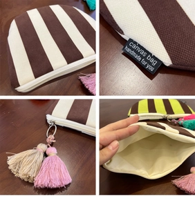 Detailed view of striped canvas makeup bag with colorful tassel and handmade fabric label