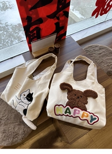 Close-up detail of cute canvas tote bags with cat and dog embroidery on wooden table