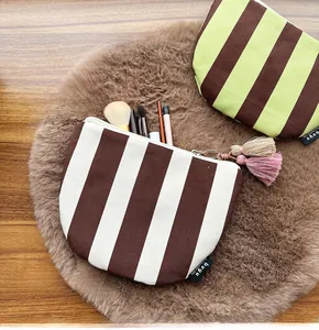 Detail of striped canvas makeup bags with tassel zippers and brush storage capacity