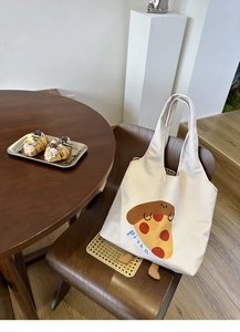 Detail of creative canvas tote with pizza print and plush feet in a cafe setting
