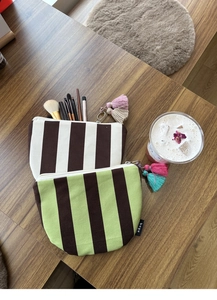Detailed close-up of striped canvas makeup bags with colorful decorative tassels