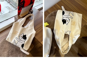 Close-up of cream canvas tote bag with cartoon cat print and 3D plush tail detail