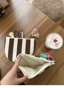 Detail of canvas makeup pouch showing waterproof white lining and colorful tassel zipper