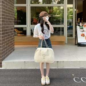 Large canvas Boston bag with letter print shown in a stylish outdoor summer street style look