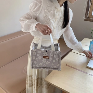Chic floral insulated lunch bag with white knit handles and elegant leather patch detail