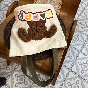 Detail of canvas tote bag with 3D teddy bear embroidery and colorful HAPPY letters