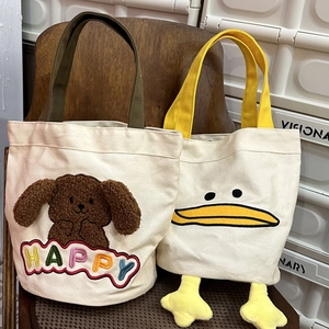 Detail of embroidered canvas bags with cute 3D plush dogs and yellow duck designs
