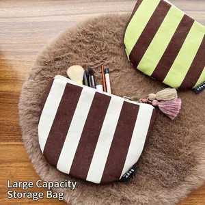 Striped canvas makeup bag with tassel charm holding various cosmetic brushes