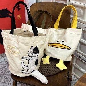Detail of canvas tote bags with cute cartoon cat embroidery and 3D plush tail features