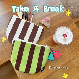 Striped canvas makeup pouches with zipper and tassel charms on wooden table