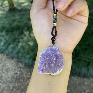 Collana con ciondolo in ametista naturale con cordino intrecciato marrone su sfondo naturale