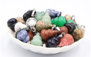 Assorted natural stone gourd pendants including obsidian and rose quartz in a white bowl