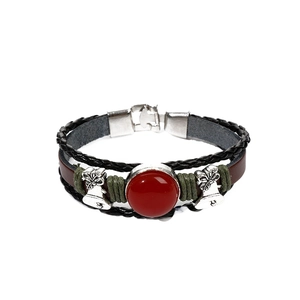 Vintage leather braided bracelet with red agate stone and silver bell charms on white background