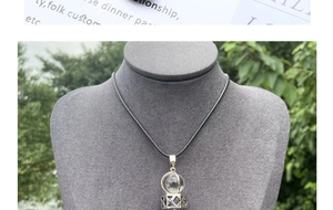 Macro detail of a clear crystal ball pendant in a silver geometric cage on a black cord