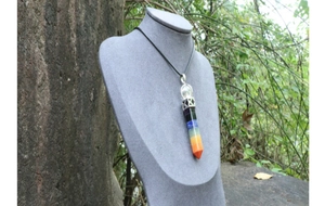 Detailed view of a seven-chakra crystal hexagonal pendant necklace on a grey mannequin