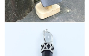 Detailed view of a hexagonal black crystal pillar pendant in a silver geometric cage frame
