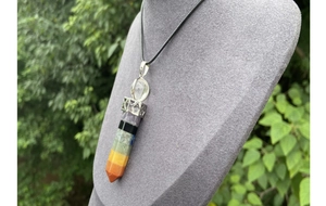 Macro detail of hexagonal 7 chakras crystal wand pendant on a black cord necklace