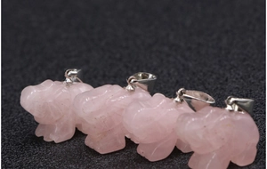 Macro-opname van vier rozenkwarts olifantshangers met zilveren clips op zwarte basis
