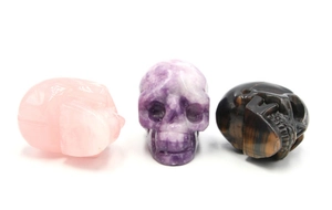 Trois crânes sculptés en quartz rose naturel, améthyste et pierre d'oeil de tigre