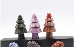 Macro detail of various colorful natural stone Christmas tree figurines on black stands
