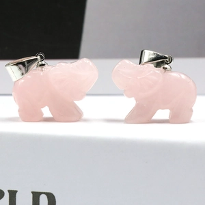 Paar gesneden rozenkwarts olifant hangers met zilveren clips op een moderne achtergrond