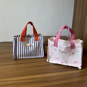 Borse tote in tela a righe con stampe a cartoni e manici colorati su tavolo in legno