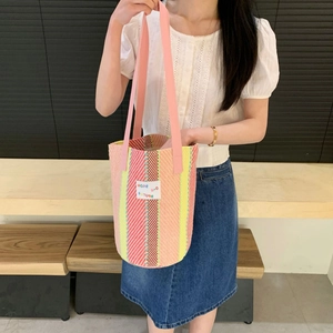 Close-up of a multi-colored striped woven tote bag with a white hope future fabric patch