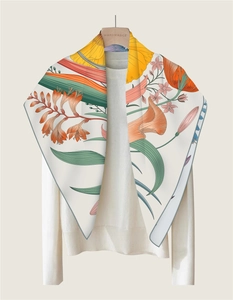 Detailed close-up of floral silk scarf with vibrant orange flowers on a white base