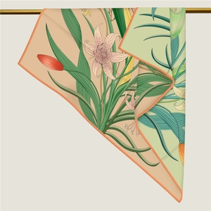 Detail of silk scarf showing elegant lily floral print and refined hand-rolled edges
