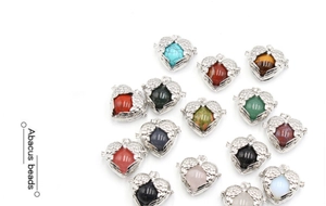 Detail view of heart-shaped angel wing lockets with various colorful gemstone beads