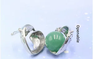 Macro shot of openable silver heart pendant with green gemstone and wing details