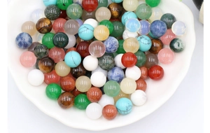 Close-up of polished 10mm assorted natural gemstone round beads in a white dish