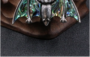 Macro shot of vintage bat pendant featuring iridescent abalone shell inlay on metal wings
