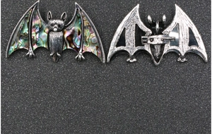 Macro view of gothic bat brooch showing antique silver finish and colorful abalone shell inlay