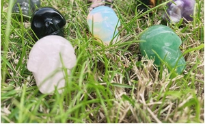 Detailed view of hand-carved natural crystal skull figurines scattered on green grass