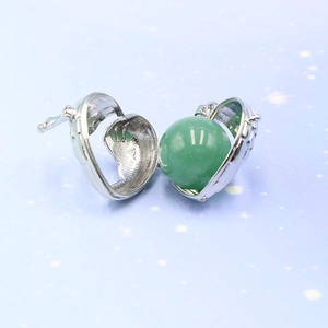 Silver hollow heart locket necklace with angel wing texture and green bead inside