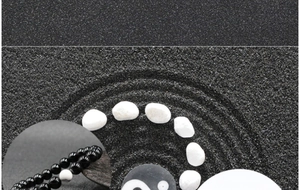 Macro shot of black agate bead bracelet with Yin Yang charm on Zen sand background
