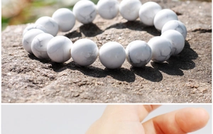 Close-up of 8mm white turquoise stone beads with marble textures on a rock surface